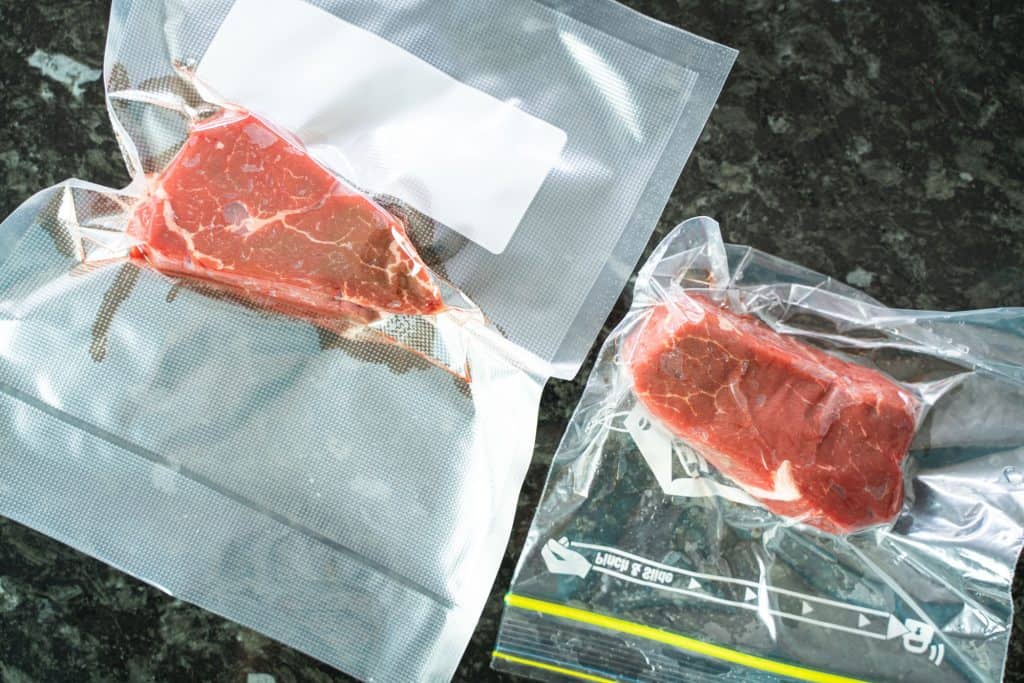 Comparative top view of a sealed zip lock bag with a steak inside, next to a bigger vacuum-sealed bag with another steak inside.