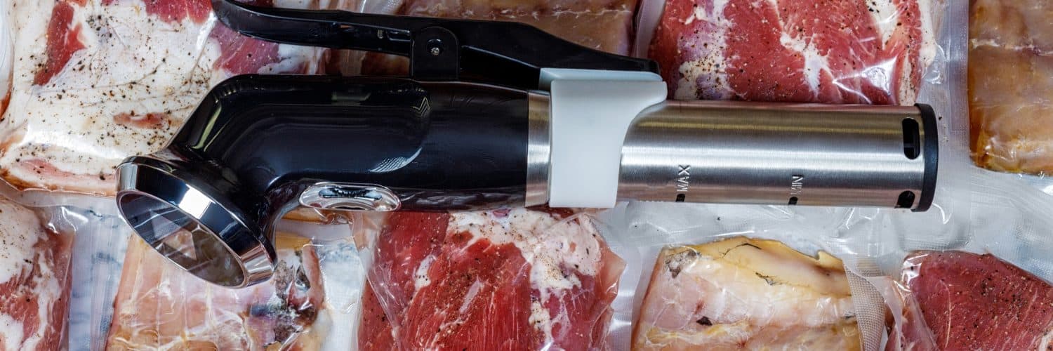 Sous vide machine next to several vacuum-sealed bags of different meats.
