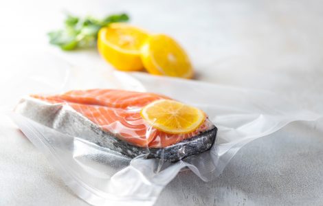 Side view of a vacuum-sealed bag with a cut of fish and lemon.