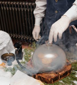 A cook using a smoking gun to infuse flavor into food.