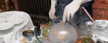 A cook using a smoking gun to infuse flavor into food.