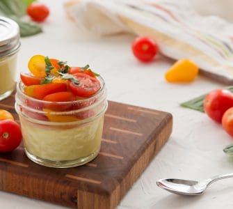Two Sous Vide Egg Bites in glass jars with tomatoes and fresh basil