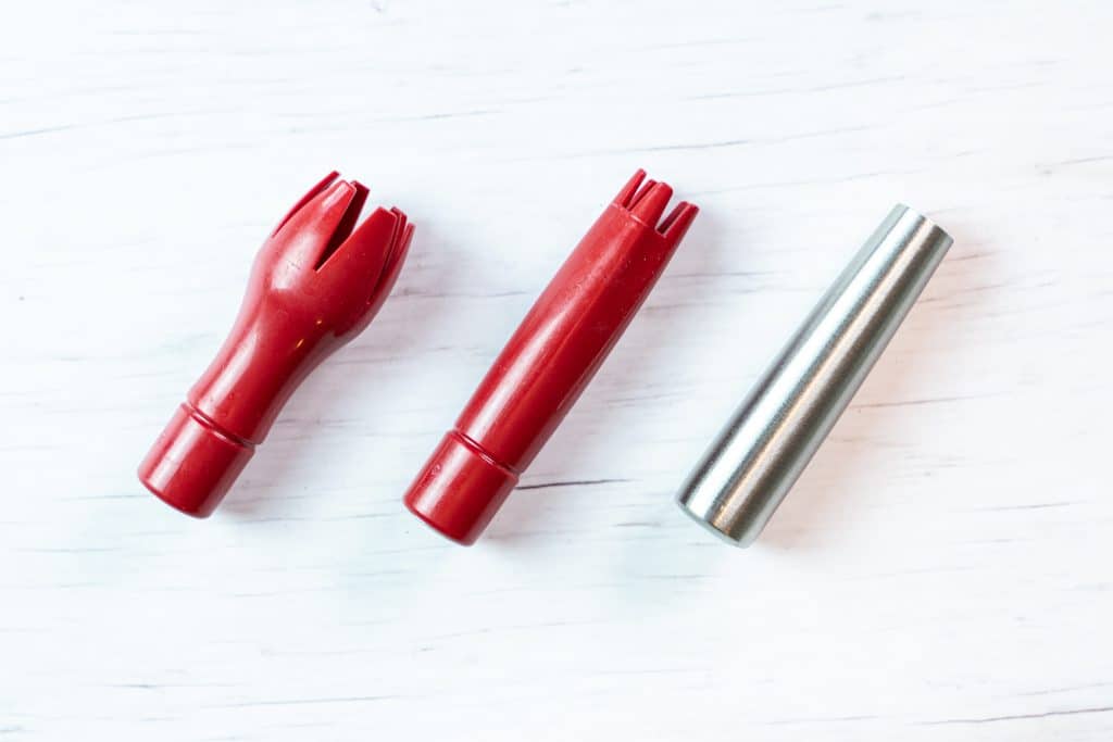 Top view of the three attachments for the Isi Whipped Cream Dispenser showing two red ones being made of plastic and one made of stainless steel.