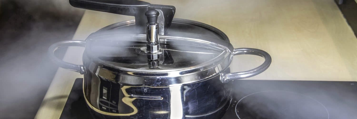 Pressure cooker with steam rapidly coming out of the top of the closed lid