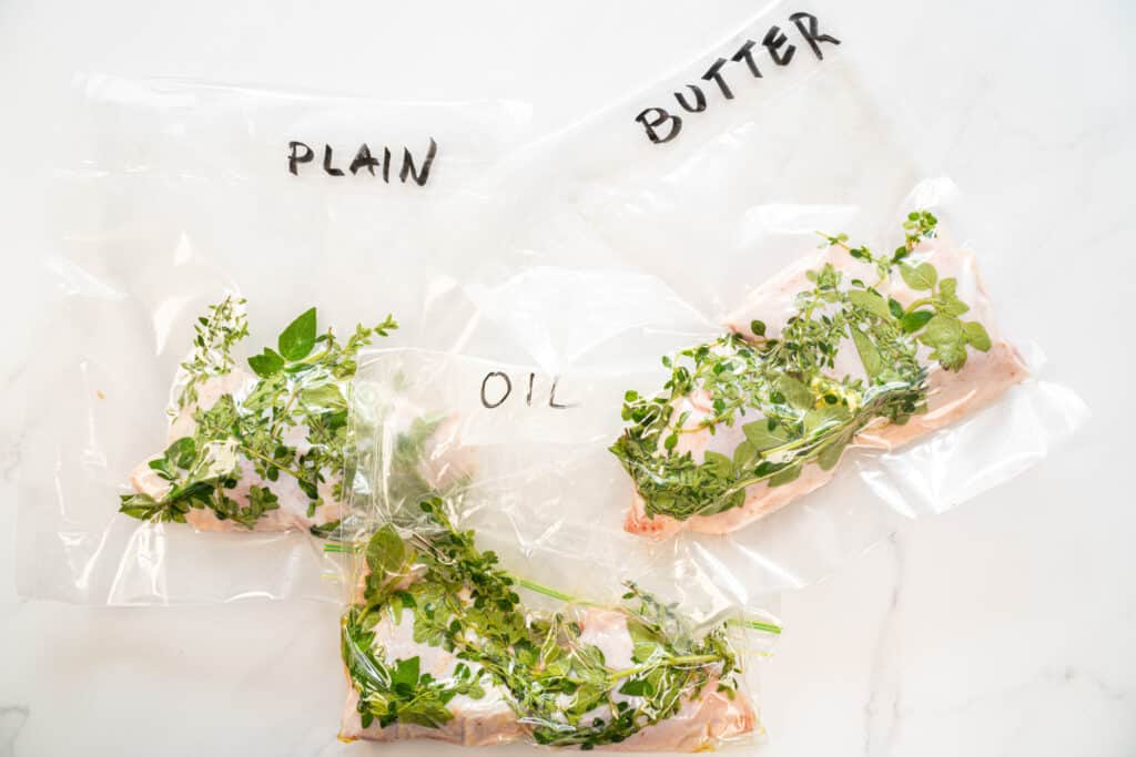 Three ziploc bags with chicken and herbs, each labeled "Plain," "Oil," and "Butter"